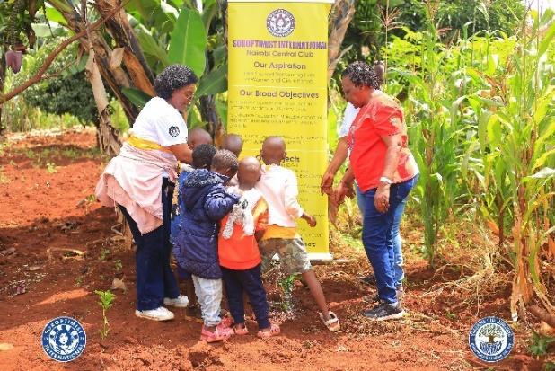 Women guiding children as they plant a fruit tree at Nairobi Children's Rescue Centre