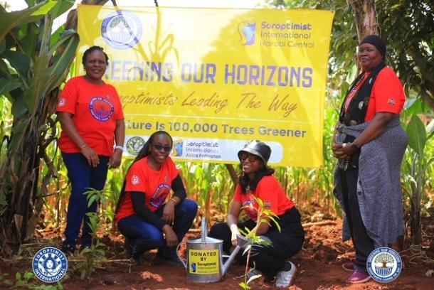Greening Our Horizons team members in red shirts beside a campaign banner